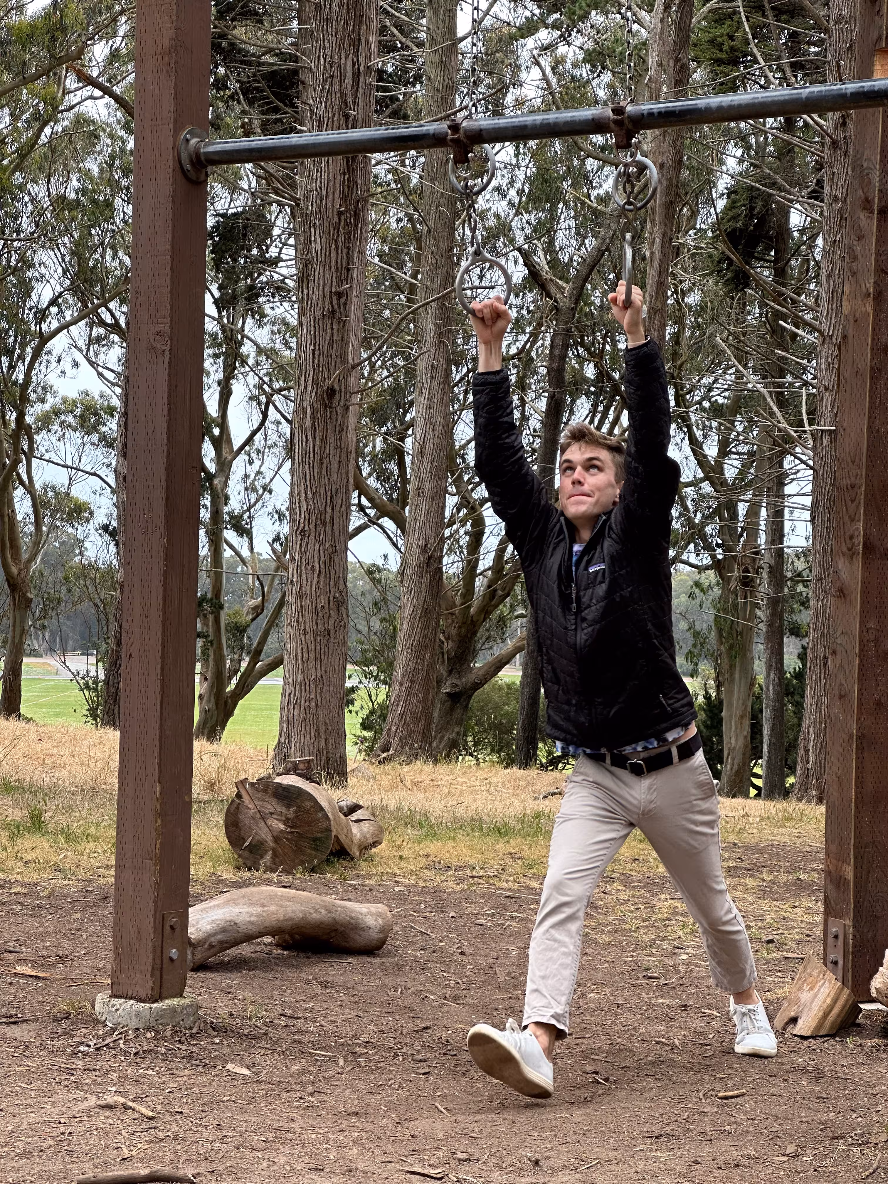 Me holding on to a pull up bar in the park, preparing to do a flip off of it.