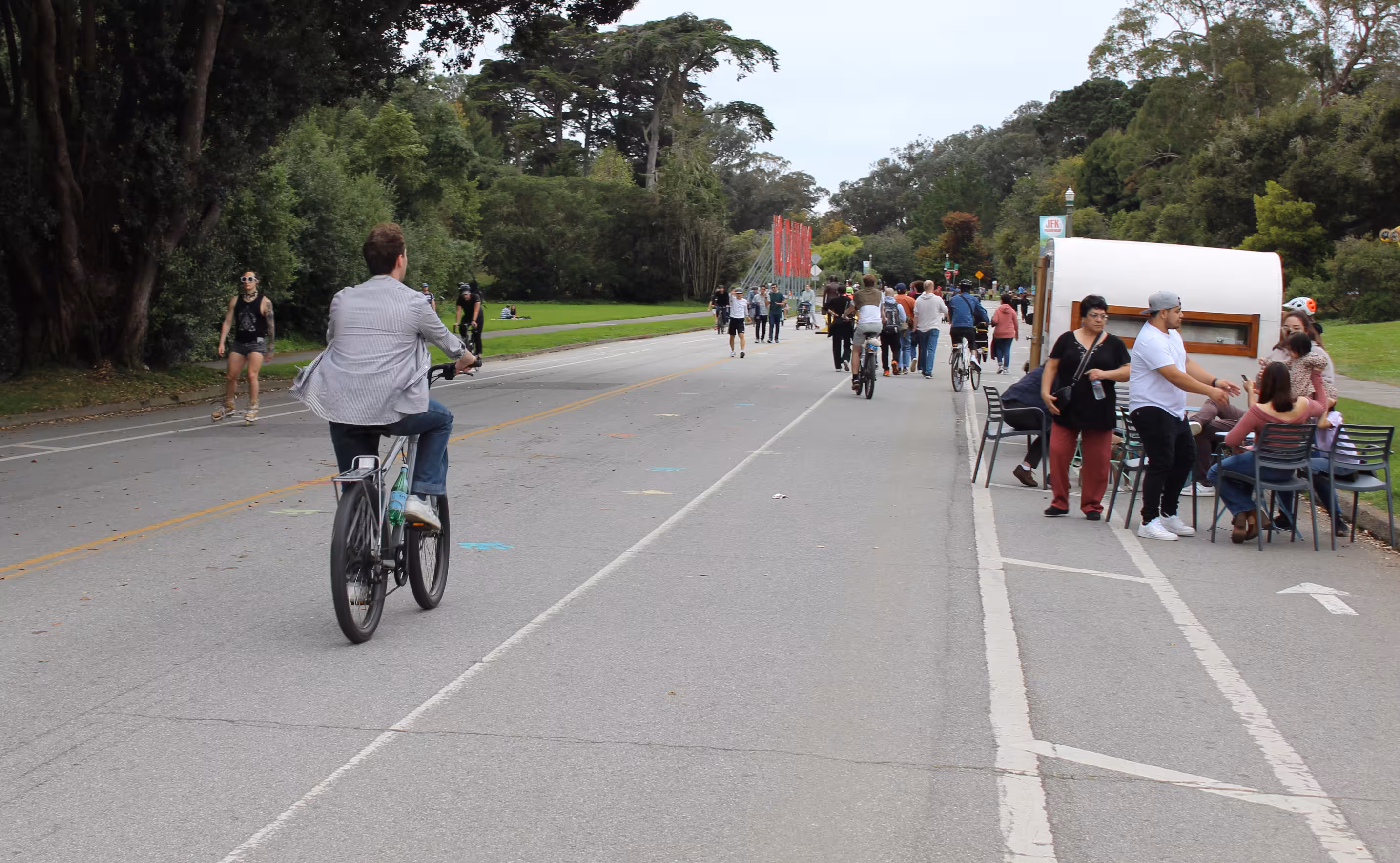 Car-Free JFK on a foggy Saturday. There are many people walking and biking, and a coffee cart on the right.